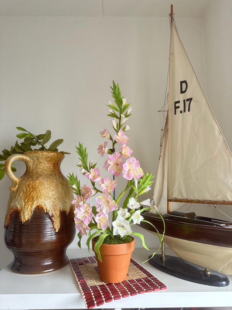 Gladiolus flowers made of realistic crepe paper in a terracotta pot.