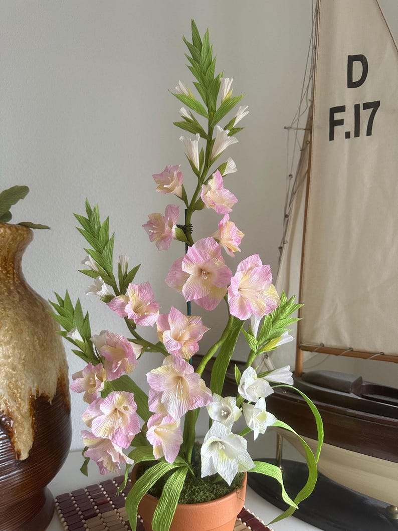 Gladiolus flowers made of realistic crepe paper in a terracotta pot.